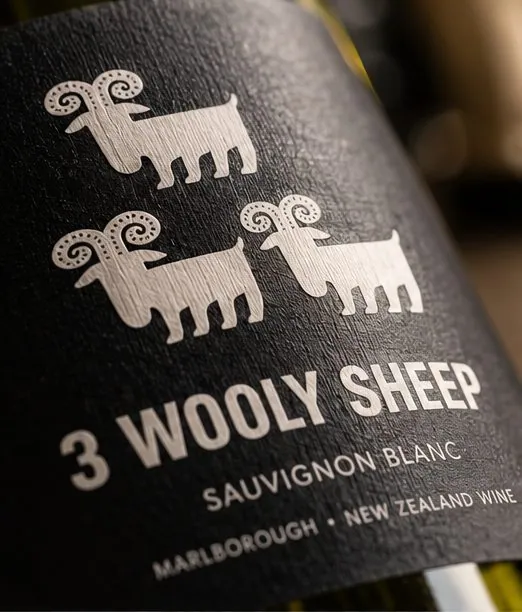 Close-up of the 3 Wooly Sheep label: three white sheep stacked above the name, variety and region on textured black stock.