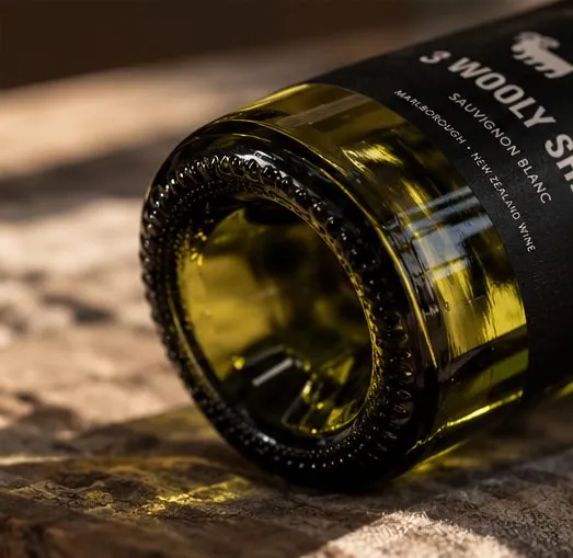 A bottle on its side showing the base and the edge of the black label.