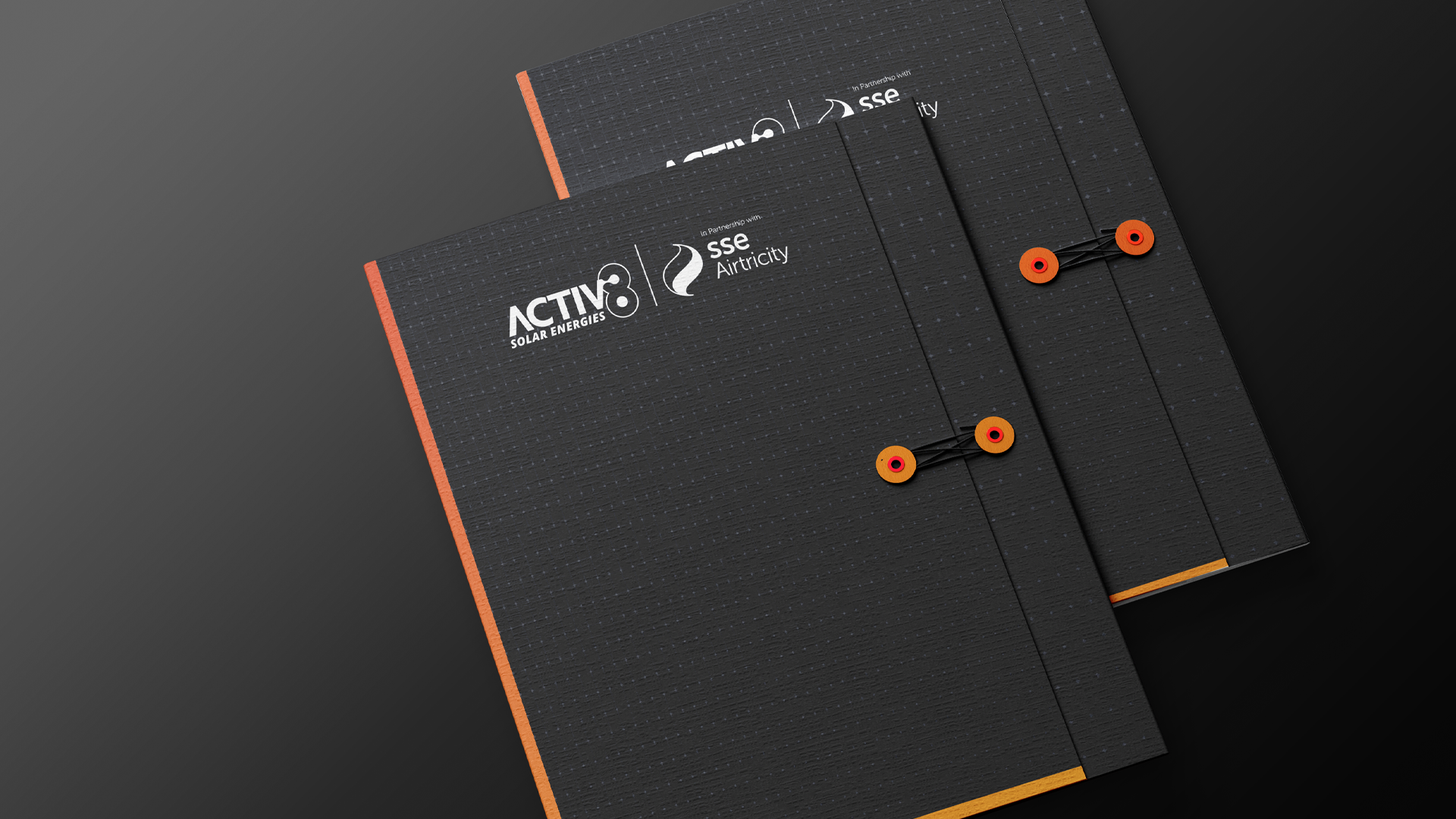 Two premium textured folders in black with orange and gold edge colouring, fastened with cord-and-disc closures