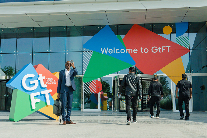 An attendee photographs the illuminated 3D 'GtFT' entrance sculpture at Google Think FinTech, Dubai