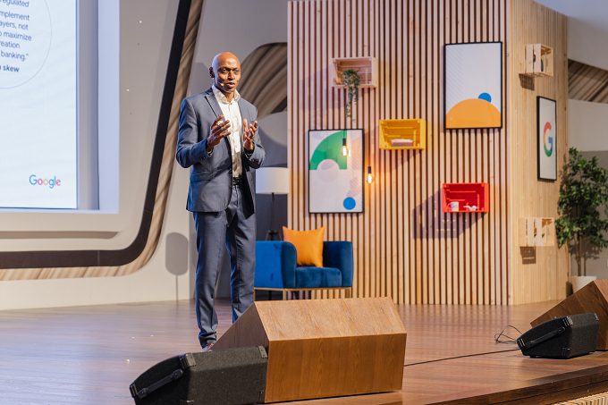 A speaker presents on the branded main stage, backed by Google colours and a custom wood-slat set design