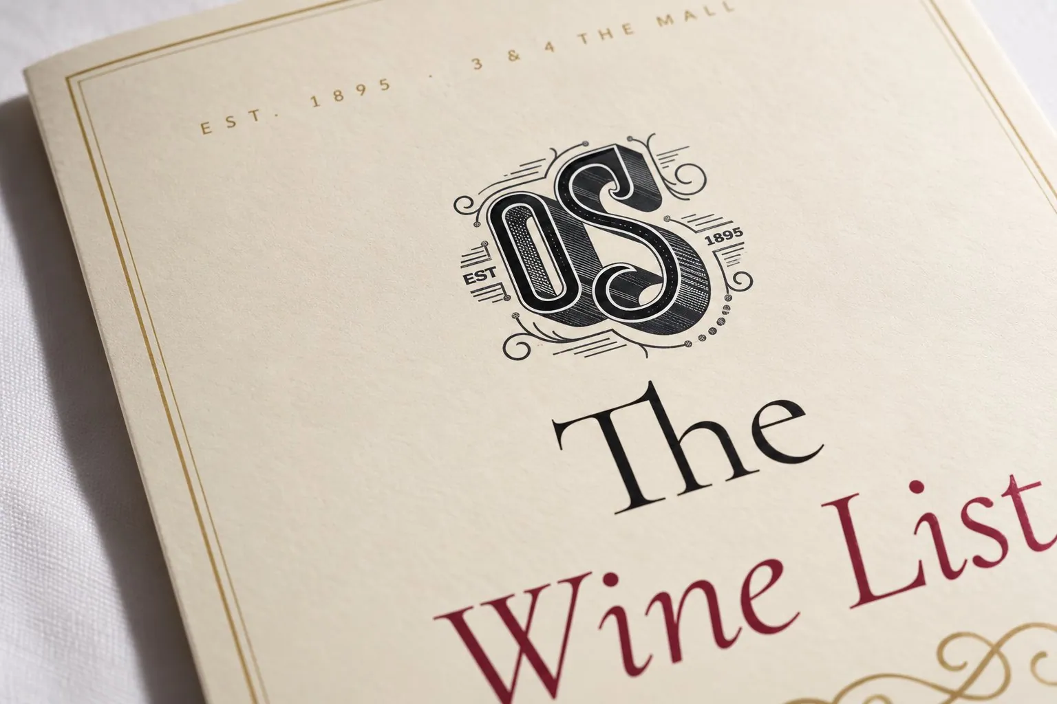 Close-up of the cover showing the OS monogram, Est. 1895 and a gold border