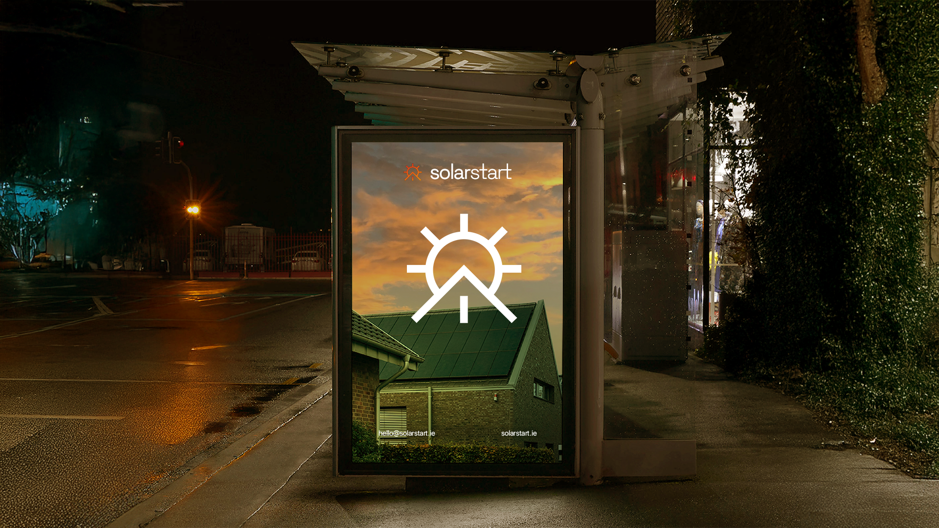 Illuminated bus shelter ad at night showing the solarstart wordmark and a large white sun-and-roofline mark over a dusk photo of a solar-panelled house